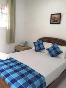 een slaapkamer met een bed met blauwe en witte kussens bij Riverside Hotel Colombo in Dandugama