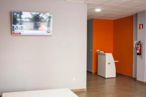 una televisione su una parete in una stanza con pareti arancioni di De Camino a Arzúa