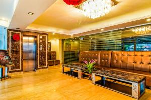 a lobby with a leather couch and a chandelier at Hotel Kenil Star in Dehradun
