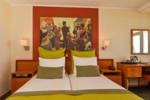 a bedroom with a bed with a painting on the wall at Hotel Noordzee in Katwijk aan Zee