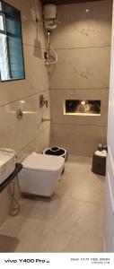 a white bathroom with a toilet and a sink at Sai Holliday's home in Alibaug