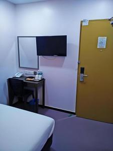 Zimmer mit einem Bett, einem Schreibtisch und einer Tür in der Unterkunft ID Hotel Yayasan in Buluh Kasap + 102 Fotos