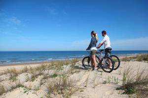 
a man and a woman riding a bike on a beach at Hotel Noordzee in Katwijk
