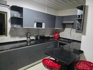 a kitchen with gray cabinets and red stools at sarahs apartments solwezi in Mpemba +7 photos