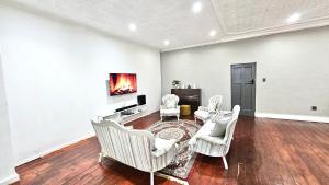 ein Wohnzimmer mit weißen Möbeln und einem Kamin in der Unterkunft Jacaranda Escape 4 x King Bed 3 Bath House in Pretoria