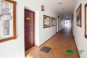 a hallway with a door and paintings on the walls at Complejo Turístico Rural Nazaret De Moguer in Moguer