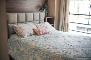 コンボリウーにあるCasa com Jacuzzi, Próximo Teleférico, GreenValley e Praia BC!のピンクの枕が付いたベッド