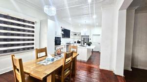 a kitchen and dining room with a wooden table and chairs at Jacaranda Escape 4 x King Bed 3 Bath House in Pretoria