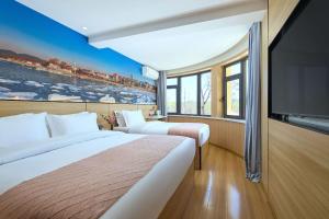 a hotel room with two beds and a flat screen tv at Floral Hotel Beidaihe Migao Intelligent Hotel in Qinhuangdao
