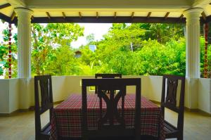 a table and chairs on a porch with a view of trees at Barefoot Beach - Hiriketiya in Dickwella