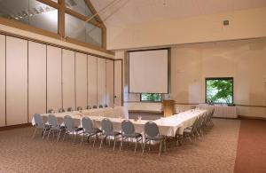 een vergaderzaal met een tafel en stoelen en een scherm bij New Harmony Inn Resort and Conference Center in New Harmony