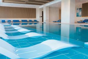a swimming pool with white chairs and a blue floor at Crowne Plaza Dushanbe by IHG in Dushanbe