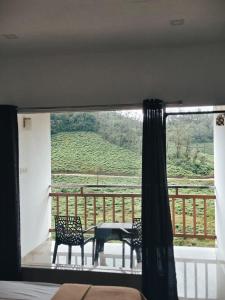 Vagamon Hill Resort في فاغامون: غرفة مع شرفة مع طاولة وكراسي