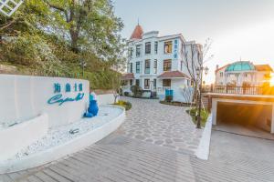 a large white house with a building at Hando • Cape Seven Seaside Villa in Qingdao