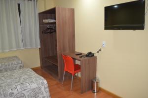 a room with a desk with a bed and a television at Hotel La Costa - Adults Only in Rio de Janeiro