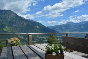 a wooden bench sitting on a table with a view of mountains at Brünnl's Försterhütte in Parcines