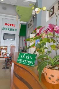 邦美蜀Sao Khue 2 Hotel的房间里有一个标牌，桌子上放着一盆植物。