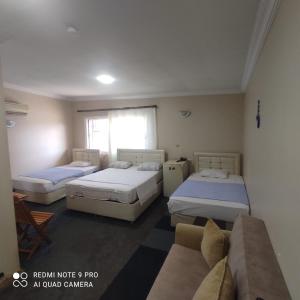 a room with three beds and a couch at Evim Butik Otel in Seyhan