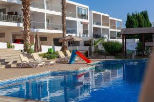 a swimming pool with chairs and an umbrella next to a building at estéa - Peyia's Pearl - Holiday Studio in Peyia
