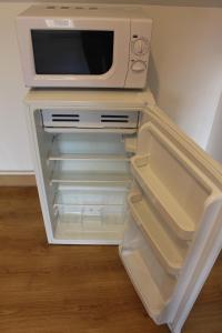 a microwave sitting on top of an empty refrigerator at Escapade au Mont St Michel in Pleine-Fougères