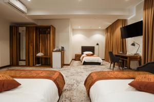 a hotel room with two beds and a desk at Bogishamol Hotel in Andijan