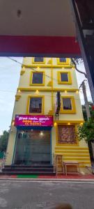 a yellow building with a sign in front of it at Nirmal Guest House in Marakkānam
