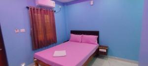 a small bedroom with a pink bed with a pink pillow at Nirmal Guest House in Marakkānam