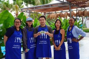 een groep mensen in blauwe uniformen die een bord met eten vasthouden bij Star City Riverside Hotel By Haviland in Da Nang