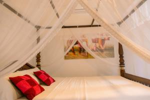 a bedroom with a white bed with red pillows at Barefoot Beach - Hiriketiya in Dickwella