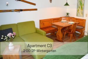 a living room with a table and a green couch at Ferienhaus Albmatte-Naturidyll am Fluss-Novemberaktion-Sauna inklusive in St. Blasien