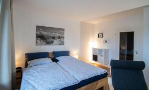 een slaapkamer met een blauw bed en een stoel bij Ruhige See in Borkum