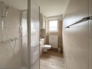 een badkamer met een toilet en een glazen douchedeur bij Ruhige See in Borkum