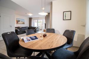 een woonkamer met een houten tafel en stoelen bij Ferienhaus Auszeit in Borkum