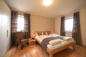 een slaapkamer met een bed en een bureau en twee ramen bij Ferienhaus Auszeit in Borkum