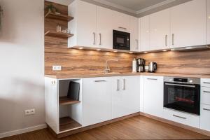 a kitchen with white cabinets and a sink at fien un moje in Borkum +2 photos