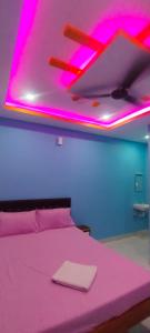 a room with a bed with pink lights on the ceiling at Nirmal Guest House in Marakkānam +3 photos
