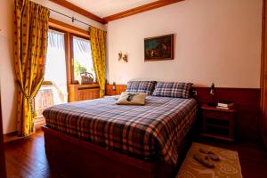 a bedroom with a bed with a plaid blanket and a window at Nido Ampezzano - a short walk from the center in Cortina dʼAmpezzo
