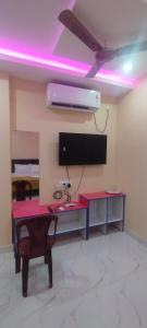 a room with a desk and a tv and purple lights at Nirmal Guest House in Marakkānam
