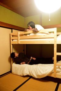 2 personen slapen op een stapelbed in een kamer bij ゲストハウス灯 in Azumino