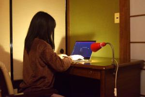 een vrouw aan een bureau met een laptop bij ゲストハウス灯 in Azumino +4 foto's