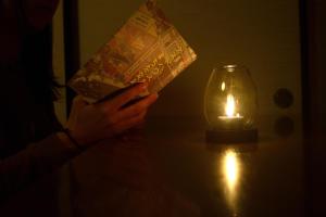 een persoon die een boek leest naast een kaars bij ゲストハウス灯 in Azumino