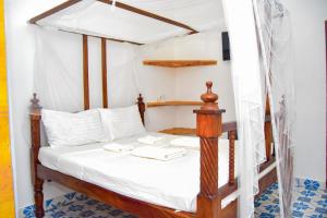 ワタムにあるRhino Apartmentsのベッドルーム(白いシーツを使用した天蓋付きベッド1台付)