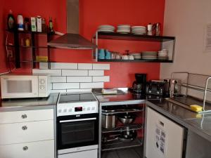 Una cocina con paredes rojas y una estufa. horno superior en Grundarfjördur Hostel, en Grundarfjordur 30 fotos más