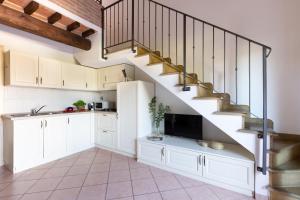 Una cocina con gabinetes blancos y una escalera. en Hotiday Apartments Costa degli Etruschi, en Vada 5 fotos más