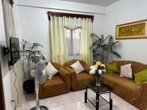 a living room with a couch and a fan at GSB City Apartelle in Tuguegarao City
