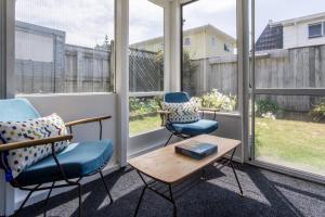 a screened in porch with two chairs and a table at Sea Breeze On Belt - near beach & coastal walk in New Plymouth