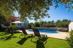 two chairs in a yard with a swimming pool at My Dalmatia - Holiday home Emily with private pool in Raštević