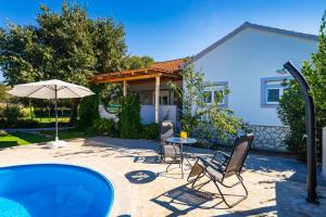 a patio with a table and chairs and an umbrella at My Dalmatia - Holiday home Emily with private pool in Raštević