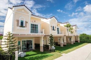 a large white house with a green yard at Dojo Hostel in Chiang Mai