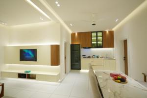 Royale Suites - 1 BHK Serviced Apartment في Kadayirippu: مطبخ مع طاولة طعام وتلفزيون +24 صورة